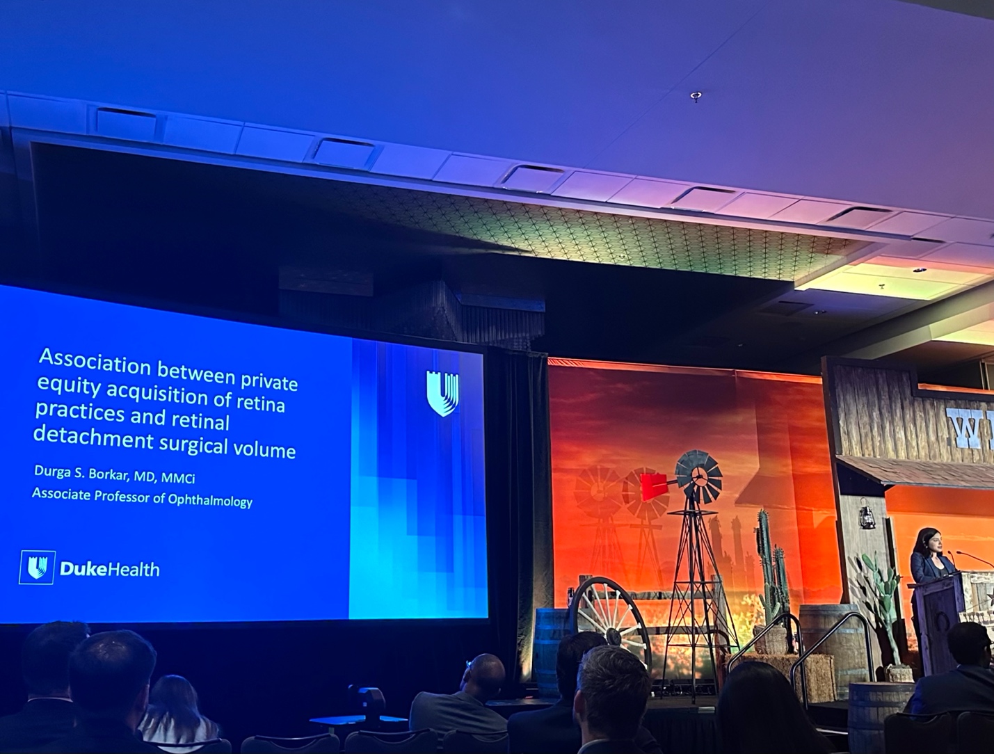 A group of people in front of a large screen Description automatically generated