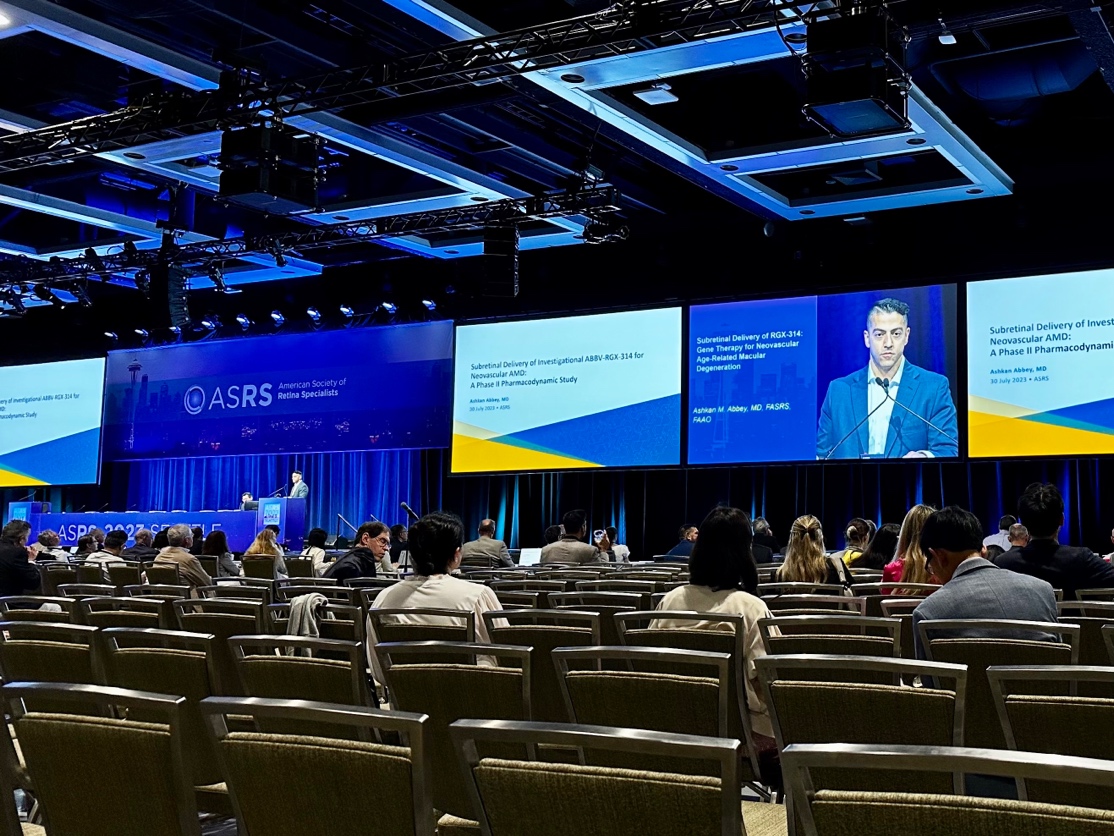A group of people sitting in chairs in a room with large screens Description automatically generated