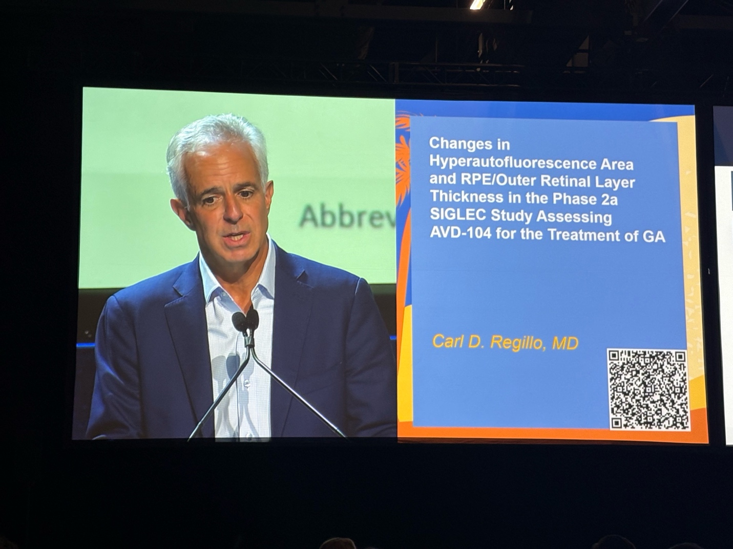 A person in a suit standing in front of a microphone  AI-generated content may be incorrect.