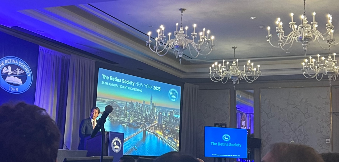 A person standing at a podium with a microphone Description automatically generated